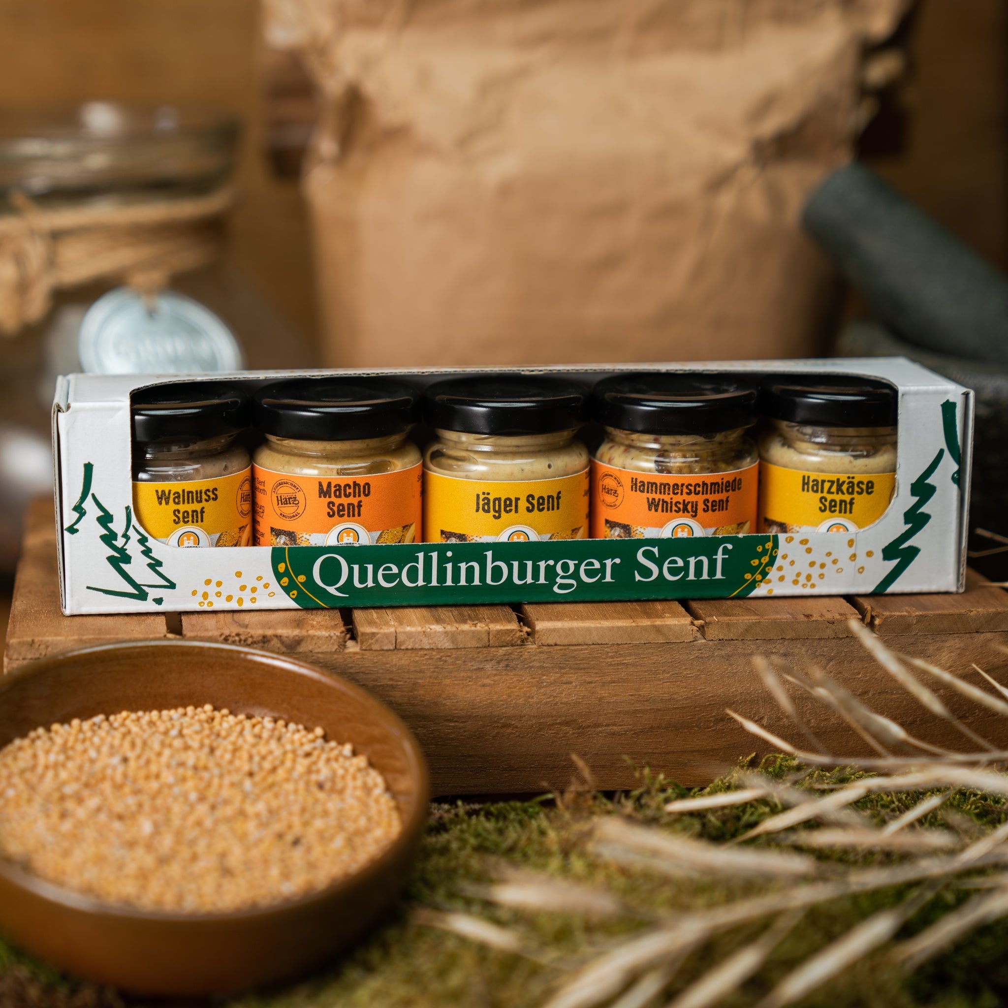 Präsentpaket mit fünf kleinen herben Senfgläsern auf rustikalem Holz. Harzer Männer-Set mit kräftigen, würzigen Sorten – inspiriert von Handwerk & Jagd.