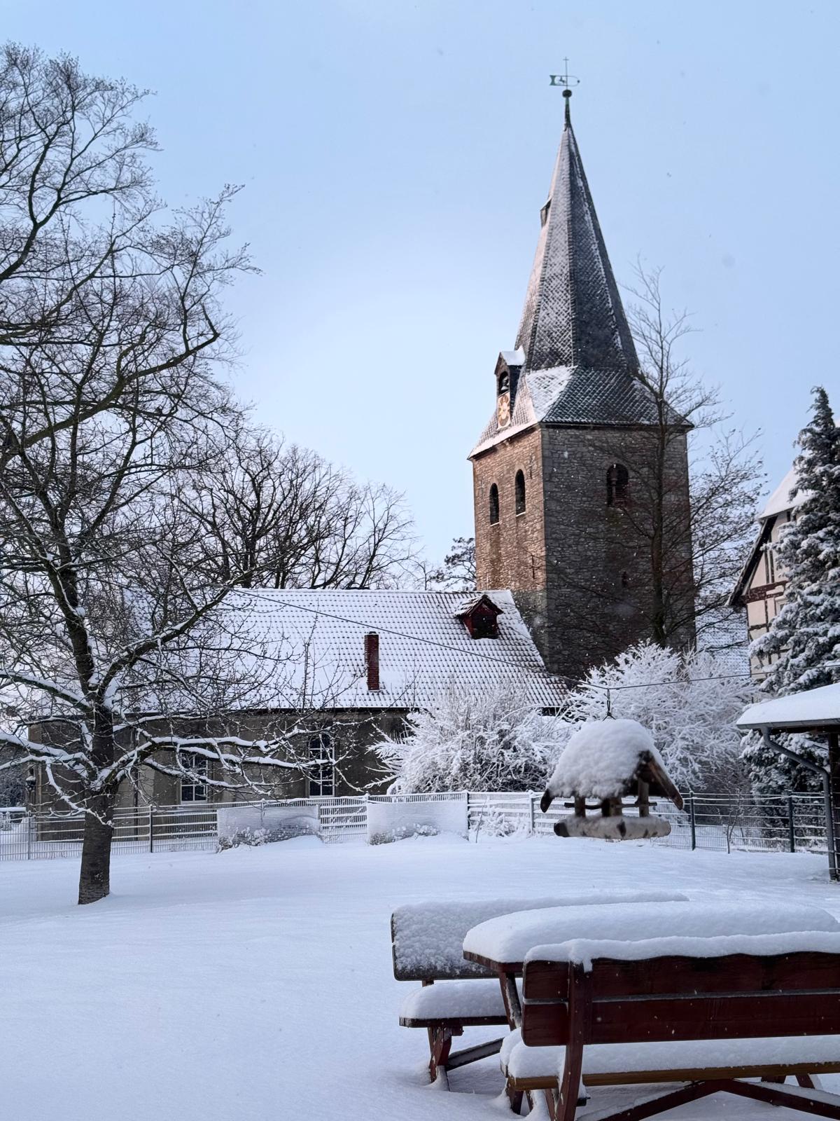 Dorfmitte mit Kirchturm im Schnee, blauer Himmel