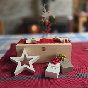 Holzkassette auf rotem Tuch mit Weihnachtsdekoration