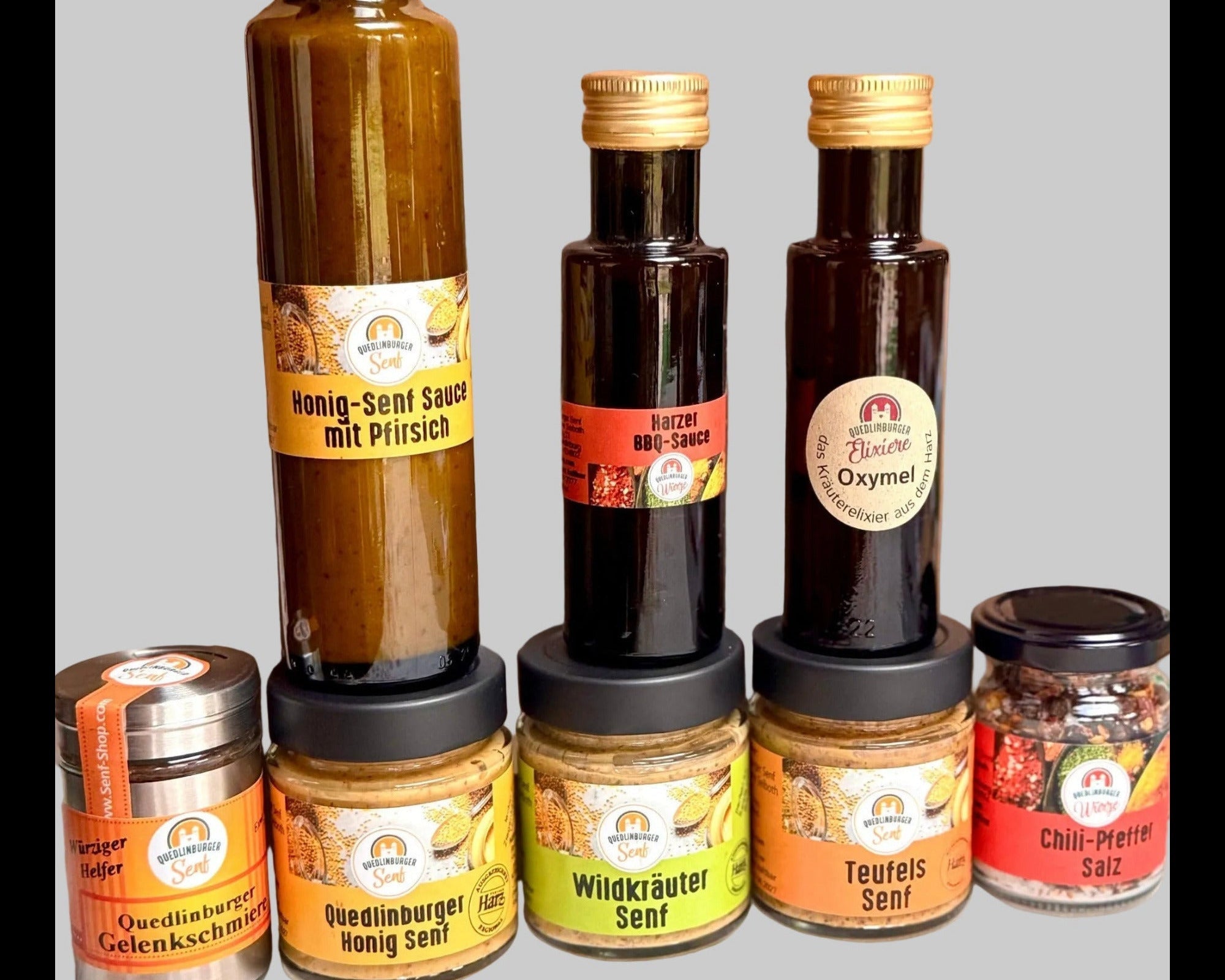 Unsere Jubiläums-Produkte: 3x Senf, scharfes Salz, milde Honig-Senf-Sauce, BBQ-Sauce und Gelenkschmiere auf dem Tisch
