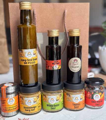 Unsere Jubiläums-Produkte: 3x Senf, scharfes Salz, milde Honig-Senf-Sauce, BBQ-Sauce und Gelenkschmiere auf dem Tisch