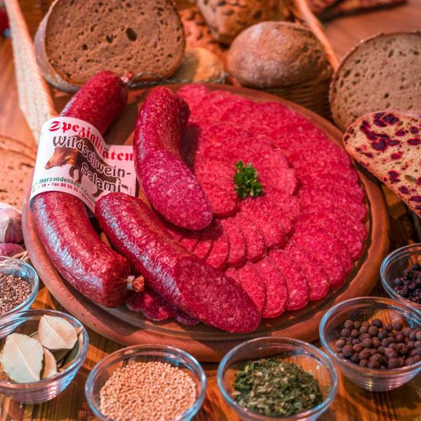 Wildschwein-Salami aus dem Harz, luftgetrocknete Wildsalami aus Wildschweinfleisch, angeschnitten auf Holzbrett, rustikale Präsentation